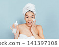 Happy woman uses facial care routine against plain background 141397108