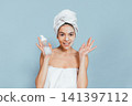 Happy woman shows skincare product after bath 141397112