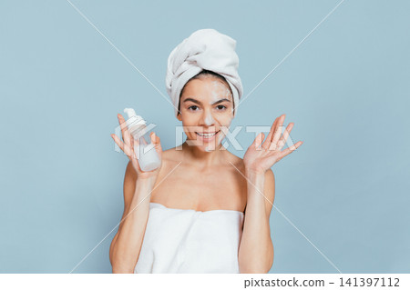 Happy woman shows skincare product after bath Happy woman shows skincare product after bath 141397112