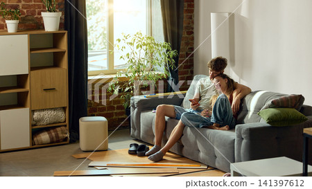 Young couple browsing renovation products on smartphone at home Young couple browsing renovation products on smartphone at home 141397612