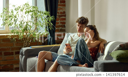 Young couple browsing home decor online on smartphone together Young couple browsing home decor online on smartphone together 141397614