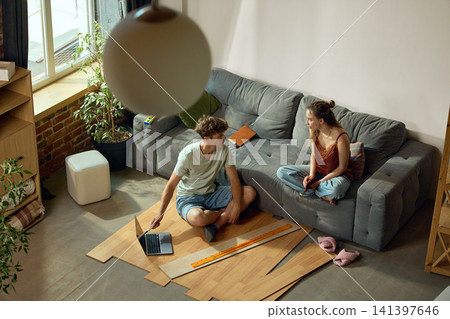 Young couple measuring flooring samples in new apartment Young couple measuring flooring samples in new apartment 141397646