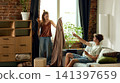 Woman holding curtain fabric while partner compares options online 141397659