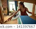 Woman measuring wooden shelving unit during apartment renovation 141397667