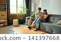Young couple comparing furniture prices on smartphone in new apartment 141397668