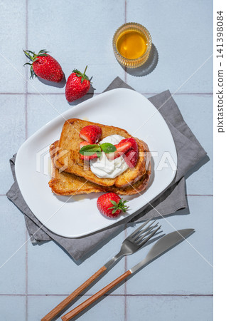 Brioche toasts with strawberries and whipped cream, drizzled with honey on a plate Brioche toasts with strawberries and whipped cream, drizzled with honey on a plate 141398084