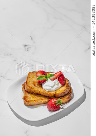 Brioche toasts with strawberries and whipped cream, drizzled with honey on a plate Brioche toasts with strawberries and whipped cream, drizzled with honey on a plate 141398085