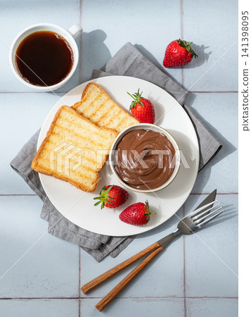 Toasted bread with chocolate cream and strawberry on a plate on a tile background Toasted bread with chocolate cream and strawberry on a plate on a tile background 141398095