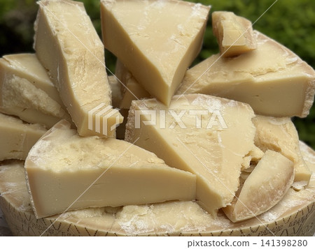 Parmesan cheese slices stacked on wooden board with green background for culinary presentation Parmesan cheese slices stacked on wooden board with green background for culinary presentation 141398280