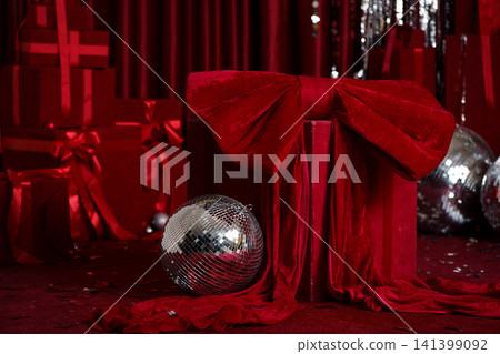 Glamorous New Year's decor with a large red velvet bow and disco balls at a party Glamorous New Year's decor with a large red velvet bow and disco balls at a party 141399092