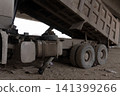Large dump truck with a raised bed parked on a dirt construction site 141399266