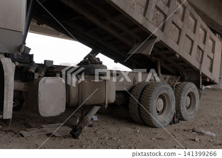 Large dump truck with a raised bed parked on a dirt construction site Large dump truck with a raised bed parked on a dirt construction site 141399266