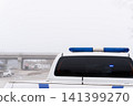White police vehicle with blue emergency lights parked in foggy outdoor setting 141399270