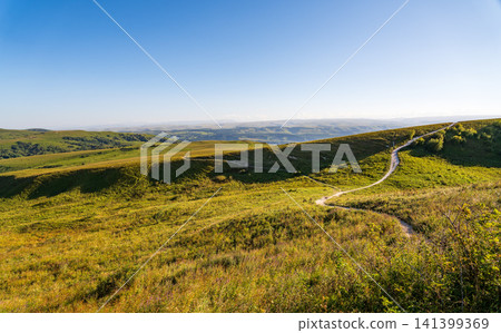 Layers of green mountains and hills in the haze during sunset. Panoramic View of Green hills and Meadow. 141399369