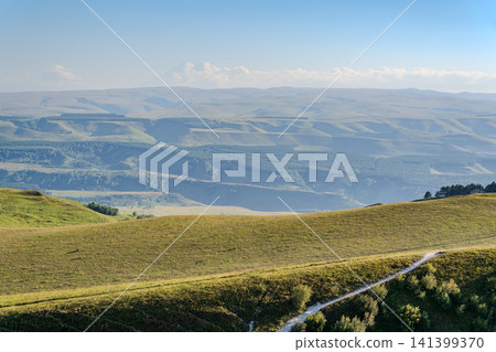 Layers of green mountains and hills in the haze during sunset. Panoramic View of Green hills and Meadow. 141399370
