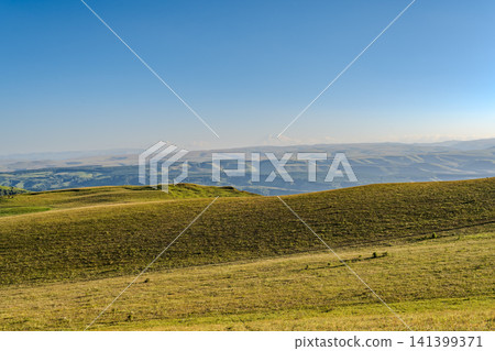 Layers of green mountains and hills in the haze during sunset. Panoramic View of Green hills and Meadow. 141399371