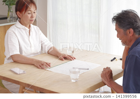 A senior couple discusses their divorce while looking at divorce papers. 141399556