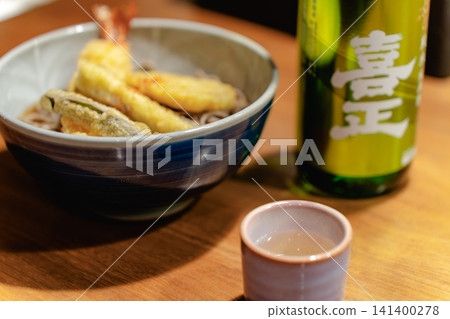 一杯清酒盛在小杯子裡,旁邊是一餐。 一杯清酒盛在小杯子裡,旁邊是一餐。 141400278