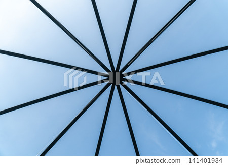 A composition looking up at the roof framework spreading radially against the blue sky. A composition looking up at the roof framework spreading radially against the blue sky. 141401984