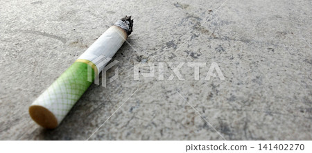 Used cigarette butt with green menthol filter on concrete surface Used cigarette butt with green menthol filter on concrete surface 141402270
