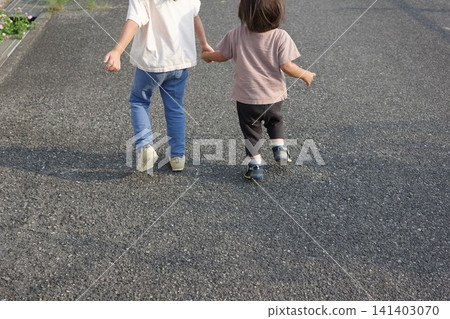 The backs of two children walking down the street, holding hands. The backs of two children walking down the street, holding hands. 141403070