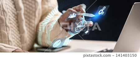 A close-up of a person using a stylus to interact with a holographic digital interface showing icons for skills development, strategy, and business management in a modern office environment A close-up of a person using a stylus to interact with a holographic digital interface showing icons for skills development, strategy, and business management in a modern office environment 141403150