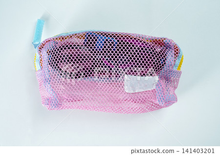 Top-down view of a swimming goggles in a pink mesh zippered storage pouch isolated on a white background Top-down view of a swimming goggles in a pink mesh zippered storage pouch isolated on a white background 141403201