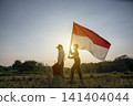 Silhouette of two young Indonesian students walking at sunset, with one student holding and waving the Indonesian national flag. Hari Kemerdekaan, Merdeka, and Dirgahayu Indonesia on 17 Agustus 141404044