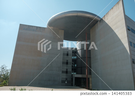 minimalist architecture: Modern building with sleek concrete walls and striking circular metallic overhang. Industrial design with clean lines and bold presence, perfect for urban lifestyle concepts. 141405383