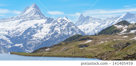Scenic view of Bachalpsee Lake with Snow Capped Swiss Alps mountain at Grindelwald First, Switzerland. Beautiful landscape in Jungfrau Region. famous Europe summer hiking trail and travel destination Scenic view of Bachalpsee Lake with Snow Capped Swiss Alps mountain at Grindelwald First, Switzerland. Beautiful landscape in Jungfrau Region. famous Europe summer hiking trail and travel destination 141405459