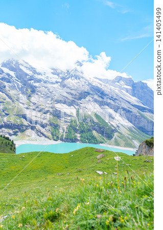 Scenic landscape of Oeschinensee or turquoise Oeschinen Lake in summer under blue sky with wildflowers and Stunning Swiss Alps. Spectacular green meadow hiking trail view, Kandersteg, Switzerland Scenic landscape of Oeschinensee or turquoise Oeschinen Lake in summer under blue sky with wildflowers and Stunning Swiss Alps. Spectacular green meadow hiking trail view, Kandersteg, Switzerland 141405499