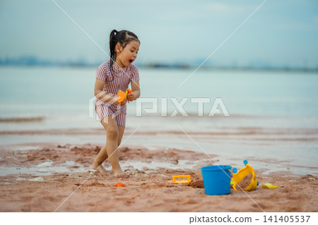 happy preschool child girl walking while holding sand toy on the sea beach in Pattaya, Thailand happy preschool child girl walking while holding sand toy on the sea beach in Pattaya, Thailand 141405537