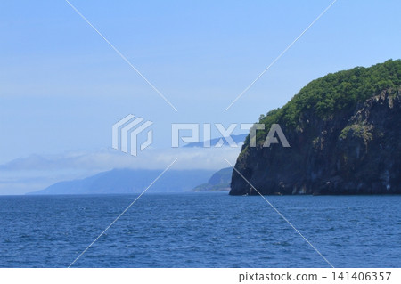 A seascape over the Shiretoko Peninsula with low, band-like clouds floating in the air. A seascape over the Shiretoko Peninsula with low, band-like clouds floating in the air. 141406357