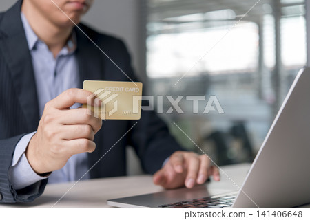 Close up businessman hand holding gold credit card and using laptop computer for online shopping. E-commerce, secure digital banking payment and corporate financial transaction concept. Close up businessman hand holding gold credit card and using laptop computer for online shopping. E-commerce, secure digital banking payment and corporate financial transaction concept. 141406648