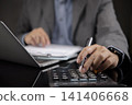 Businessman hand using calculator and pen for financial analysis, tax calculation, and budget planning at office desk. Concept of accounting, auditing, and corporate finance management. 141406668
