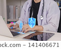 Doctor using laptop with virtual medical shield icon and human anatomy hologram. Concept of health insurance coverage, medical data protection, and digital healthcare security. 141406671