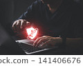 Man hand typing on laptop with red shield warning icon wrapped in chains. Concept of ransomware attack, cyber security breach, system failure, and malware danger. 141406676