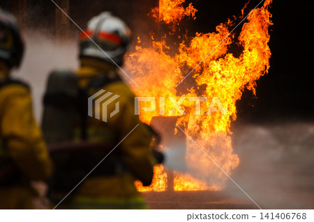 Firefighters tackling a large intense blazing fire outdoors Firefighters tackling a large intense blazing fire outdoors 141406768