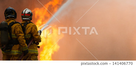 Firefighters tackling a large intense blazing fire outdoors Firefighters tackling a large intense blazing fire outdoors 141406770