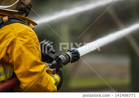 Firefighters tackling a large intense blazing fire outdoors Firefighters tackling a large intense blazing fire outdoors 141406771
