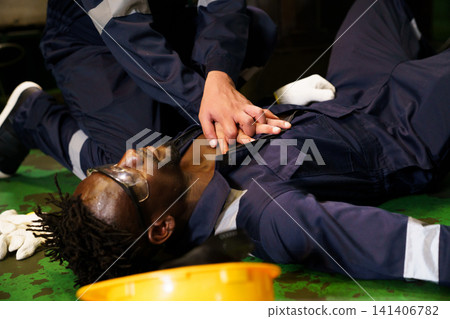 Factory worker performing cpr on unconscious colleague Factory worker performing cpr on unconscious colleague 141406782