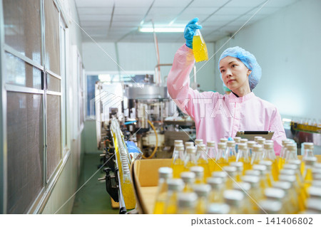 Quality control specialist examining juice bottle on production line Quality control specialist examining juice bottle on production line 141406802