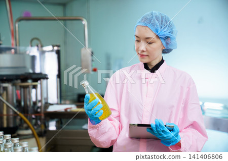 Quality control specialist examining juice bottle on production line Quality control specialist examining juice bottle on production line 141406806
