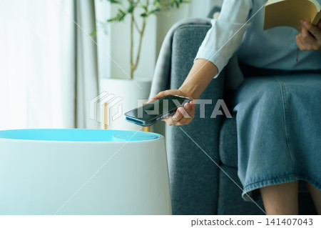 Close up of hand holding smartphone to control smart air purifier Close up of hand holding smartphone to control smart air purifier 141407043
