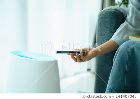 Close up of hand holding smartphone to control smart air purifier Close up of hand holding smartphone to control smart air purifier 141407045