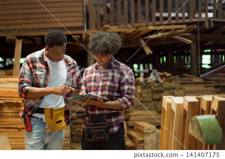 Diverse young craftsmen working together and reviewing plans in lumber mill Diverse young craftsmen working together and reviewing plans in lumber mill 141407175