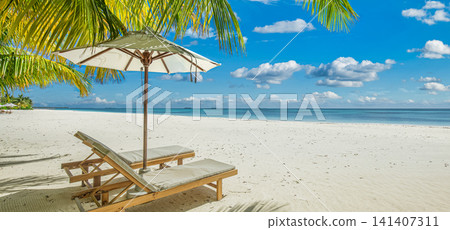 Picturesque tropical beach wooden deck chairs sun umbrella under palm fronds white sand turquoise sea blue sky. Perfect summer vacation travel landscape resort paradise. Luxury getaway relax scenic Picturesque tropical beach wooden deck chairs sun umbrella under palm fronds white sand turquoise sea blue sky. Perfect summer vacation travel landscape resort paradise. Luxury getaway relax scenic 141407311