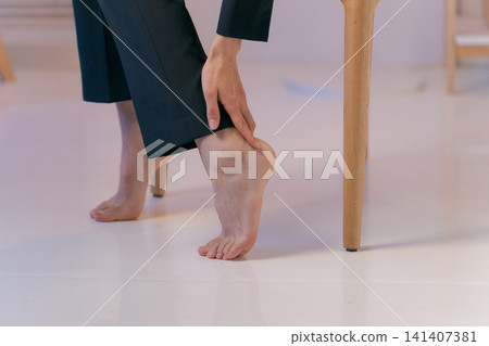 特寫鏡頭:一位身穿西裝的女子摀著腿。 特寫鏡頭:一位身穿西裝的女子摀著腿。 141407381