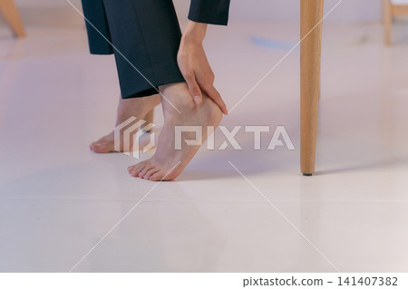 特寫鏡頭:一位身穿西裝的女子摀著腿。 特寫鏡頭:一位身穿西裝的女子摀著腿。 141407382