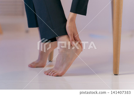 Close-up shot of a woman in a suit holding her leg. Close-up shot of a woman in a suit holding her leg. 141407383